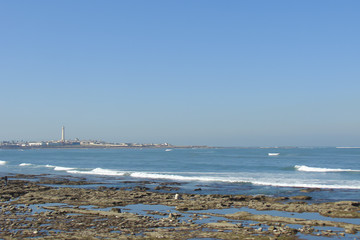 evening surf in the bay of Casablanca (Morocco), one man sitting on a rocky beach