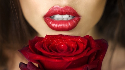 Fototapeta na wymiar Close-up beautiful female lips with bright red makeup. Perfect clean skin, sexy lip make-up. Beautiful spa portrait with tender red rose flower. Spa and cosmetics