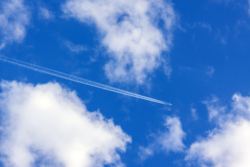 White clouds and an airplane trail in a blue sky
