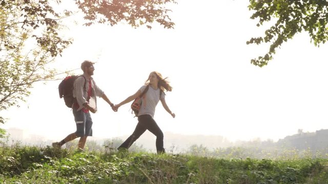 Young lovely couple backpackers tourists walking holding hands arrive on hill in front of roman aqueduct arches in parco degli acquedotti park ruins in rome on romantic misty sunrise with guitar and