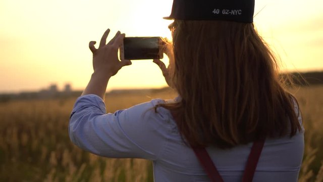 Concept Enjoyment Of Nature. Young Unidentified Woman Shoots Beautiful Nature On The Smartphone's Camera In Sunny Summer Evening