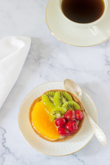 Mini cake or tart with custard and various fruits in jelly.