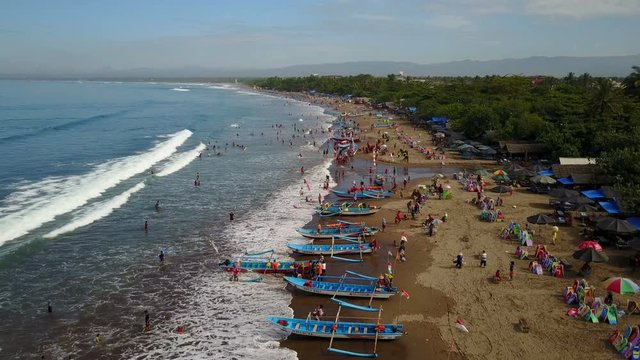 Aerial view of crowded beach with classic fishing vessels and holidaymakers in Pangandara, Indonesia