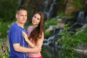 beautiful couple standing hugging each other at sunset on the nature near the waterfall, selective focus