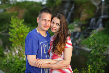 Obraz premium beautiful couple standing hugging each other at sunset on the nature near the waterfall, selective focus