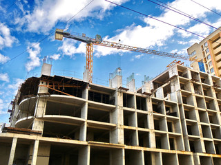 Construction crane near building under construction against blue sky. Construction site.