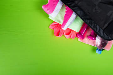 pink sportswear and accessories for fitness, a bottle of water, on a light green background with a place for recording