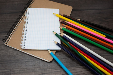 The colored pencils and a notebook on desk. Copy space