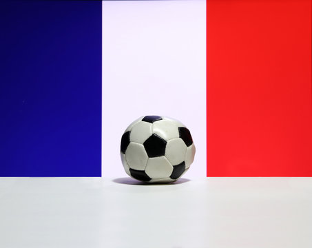 Small football on the white floor and Tri Color or blue white and red color of French nation flag background. The concept of sport.