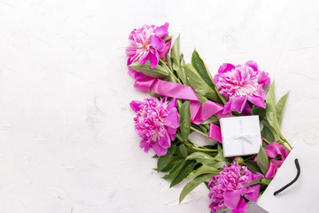 Peony bouquet in white bag and gift box on white background.
