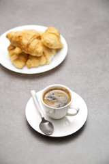 Cup of fresh coffee with croissants on dark background