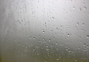 Rain drops on window glasses surface with cloudy background . Natural Pattern of raindrops isolated on cloudy background.
