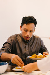 Portrait of a Malay Muslim man having a tasty breakfast meal with his wife at the dining table before Ramadan