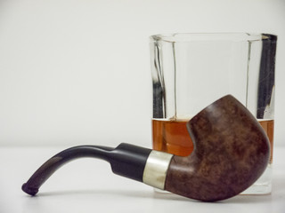 Briar smoking pipe with glass of whisky side view with white background