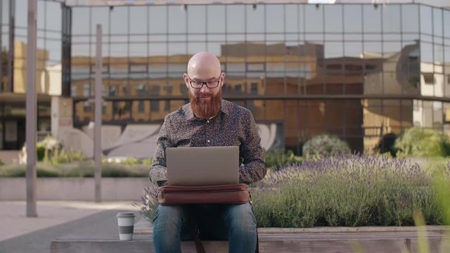 Hipster businessman with a laptop working outdoors