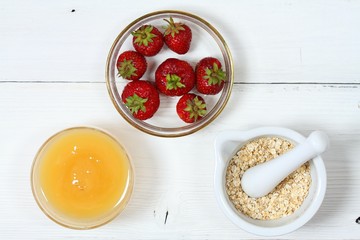 Face mask from strawberry, yogurt, oatmeal,   honey / Edible ingredients for facial mask on the white wooden board, flat lay