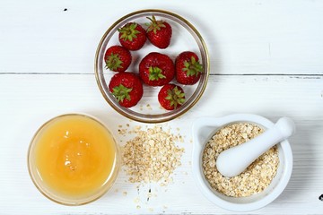 Face mask from strawberry, yogurt, oatmeal,   honey / Edible ingredients for facial mask on the white wooden board, flat lay