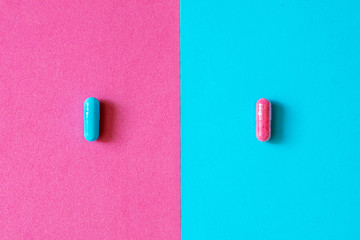 Pink and blue capsules, pills isolated on bicolor pink and blue colored background. Medication and...