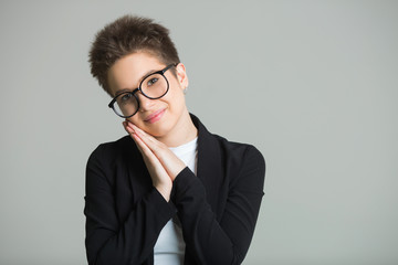 young beautiful girl with short hair on her head and with glasses with a short haircut on a gray background