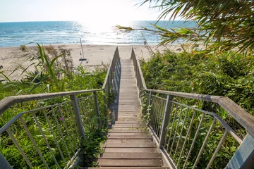 Türaufkleber Abstieg zum Strand Holztreppen, die an einem sonnigen Tag von der Klippe auf den Sand führen, Treppen aus Holzbrettern