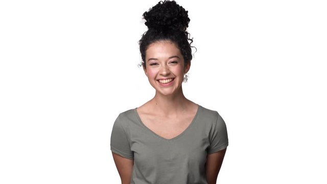 Portrait of positive curly woman 20s wearing basic t-shirt laughing to you and expressing joy, isolated over white background. Concept of emotions