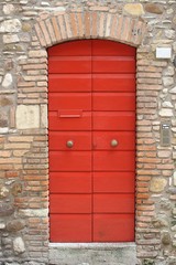 Red door in historic medieval house in Italy