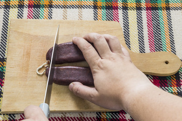 Cutting air-dried sausage. First person view.
