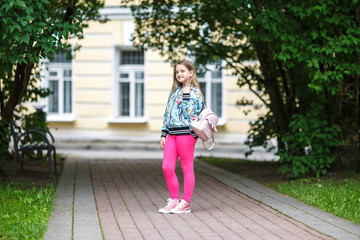 Fototapeta na wymiar portrait of little beautiful stylish kid girl with backpack in city park