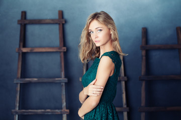 Obraz premium Cute girl on blue rustik background. Fashion portrait of young model woman in green dress.