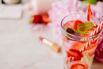 Beauty flat lay with a cosmetics, perfum, detox water with strawberry and peonies on a marble background