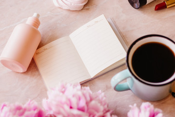 Beauty flat lay with a diary, cup of coffee, accessories and peonies on a marble background