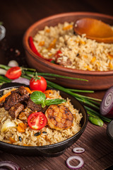 The concept of oriental cuisine. Homemade Uzbek pilaf from lamb served in cast iron cookware. Copy space.