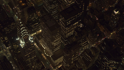 AERIAL: Lit Chrysler Building and Midtown Manhattan streets shining at night