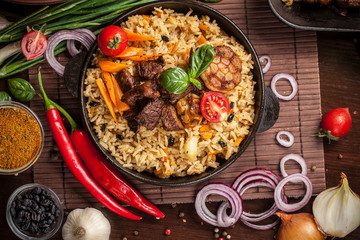 The concept of oriental cuisine. Homemade Uzbek pilaf from lamb served in cast iron cookware. Copy space.