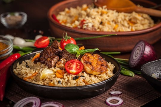 The concept of oriental cuisine. Homemade Uzbek pilaf from lamb served in cast iron cookware. Copy space.