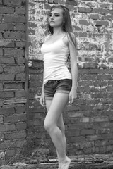 girl in a T-shirt and shorts stands by the brick wall