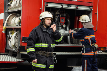 Fireman (firefighter) in action standing  near a firetruck. Emergency safety. Protection, rescue...