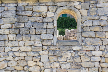 Fototapeta na wymiar wall with a window in the ruins of an ancient city overlooking the wall with a door, selective focus