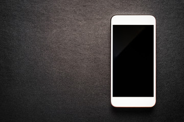 white mobile smartphone on luxury black background, top view.