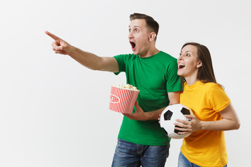 European young couple, woman, man, football fans in yellow green t-shirt cheer up support team with soccer ball bucket of popcorn isolated on white background. Sport, family leisure, lifestyle concept