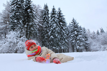 The frame depicts a winter forest, trees and pine trees. A child is playing with snow. Walk in the...