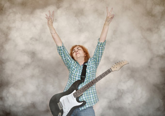 Fototapeta na wymiar Middle aged female guitarist wearing checked shirt with closed eyes and hands up showing peace sign. Smoke effect applied.