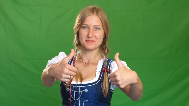 Woman in bavarian costume laughs and shows thumbs up. Green screen