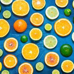 Citrus pattern on blue background. Assorted citrus fruits. Slices of orange, tangerine, lemon, lime. Top view. Square.