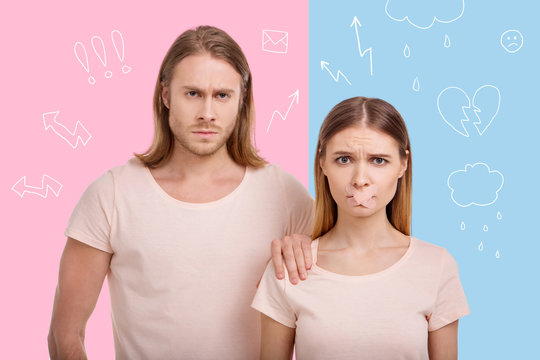 Unfair situation. Young woman experiencing gender unequality while standing near her strong boyfriend and having a plaster on her lips