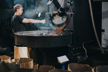 Man controlling process of roasting coffee beans in traditional machine