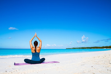 Fototapeta na wymiar Beautiful young woman practicing yoga on the beach on Bahamas iseland.
