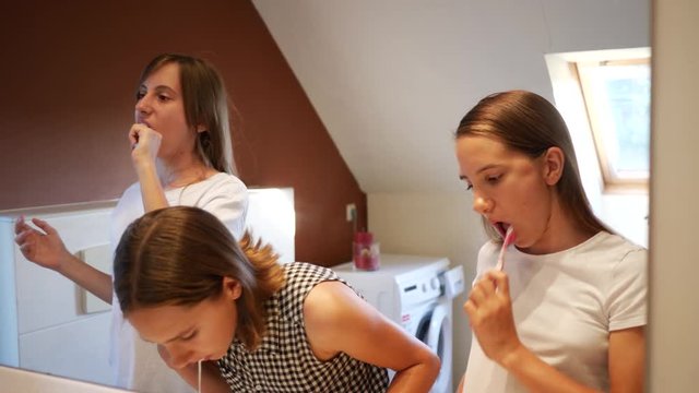 Brush teeth in front of the bathroom mirror three girls teenager sisters before going to bed