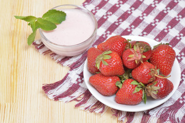 Large ripe strawberries on a white plate and sauce with mint leaf