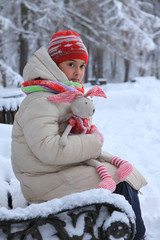 The frame depicts a winter forest, trees and pine trees. A child is playing with snow. Walk in the...
